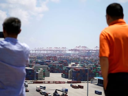 Dos hombres miran la zona de contenedores del puerto de Shanghái.