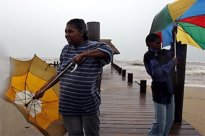 Sólo dos semanas después de que el huracán Stan pasase sobre Centroamérica, las lluvias y los fuertes vientos vuelven a Honduras. En la imagen, dos mujeres tratan inútilmente de guarecerse tras sus paraguas.