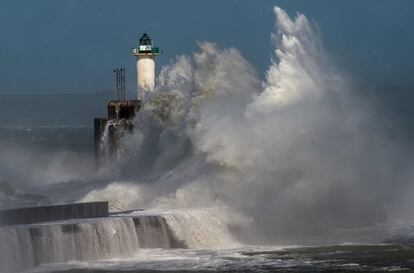 Una ola rompe contra un muelle frente de un faro en Boulogne-sur-Mer (Francia).