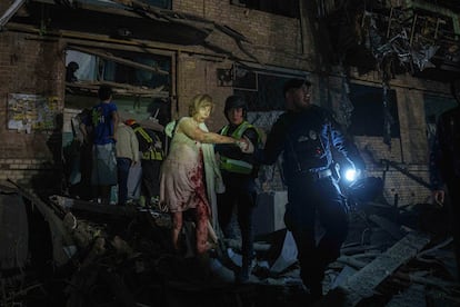 Miembros de los equipos de rescate ayudan a una mujer herida por un bombardeo ruso, en un barrio residencial de Kiev este jueves.