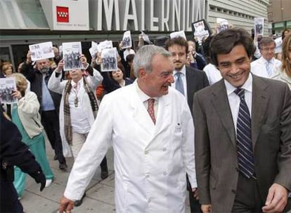 Juan José Güemes conversa con el gerente del hospital Gregorio Marañón, Antonio Barba, mientras le siguen con pancartas.