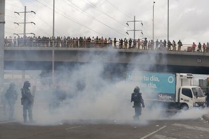 Personas observan desde un puente el enfrentamiento entre policías antidisturbios y transportistas, este jueves en la capital colombiana.