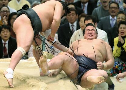 El japonés Yokozuna, Gran Campeón de Sumo Kisenosato (derecha), es lanzado fuera del ring por el mongol Yokozuna Harumafuji en el Torneo Grand Sumo de Primavera en Osaka.