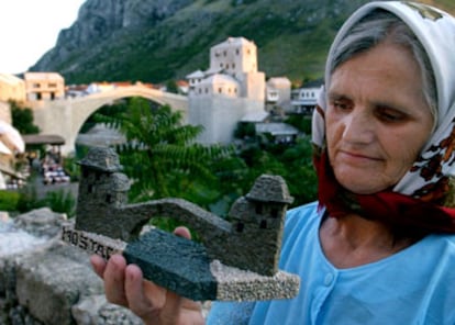 Una bosnia musulmana vende una réplica hecha a mano del Puente Viejo de Mostar en la víspera de la inauguración.