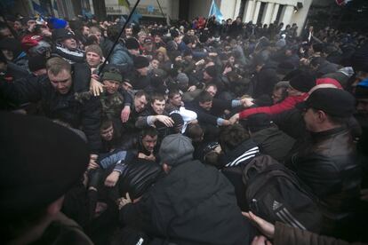 Un grupo de hombres intenta sacar a otras personas que estn atrapadas por culpa de una estampida durante una multitudinaria protesta cerca del Parlamento de Crimea (Ucrania).