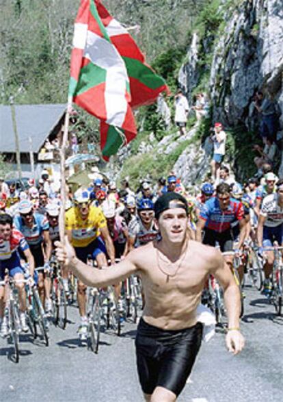 Foto de archivo de un joven corriendo delante del pelotón con una <i>ikurriña.</i>