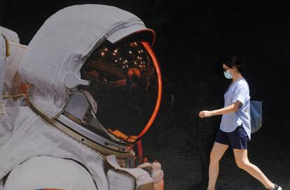 Un joven con mascarilla pasa delante de un mural por una calle de Hong Kong (China). Hong Kong y Urumqi, ciudades donde surgieron los últimos grandes rebrotes del coronavirus en China, relajarán las restricciones ante la bajada de nuevos casos de la covid-19.