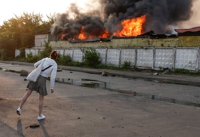 Una transeúnte observa el incendio desatado en el lugar del impacto de un dron ruso, este martes en Kiev. 