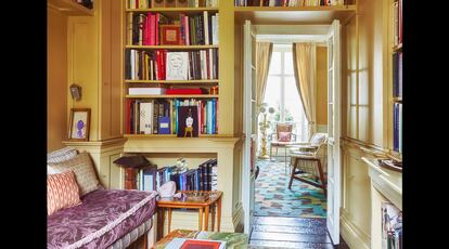 La librería se encuentra junto al salón. A la izquierda, banqueta de inspiración marroquí llena de almohadones tapizada con tejido estampado en tonos lila y púrpura.