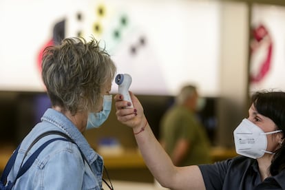 A worker takes a customer's temperature at a shopping center in Madrid.