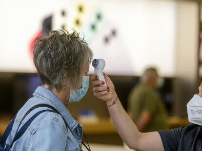 A worker takes a customer's temperature at a shopping center in Madrid.