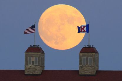 La luna se eleva sobre las banderas en la Universidad de Kansas (EE UU).