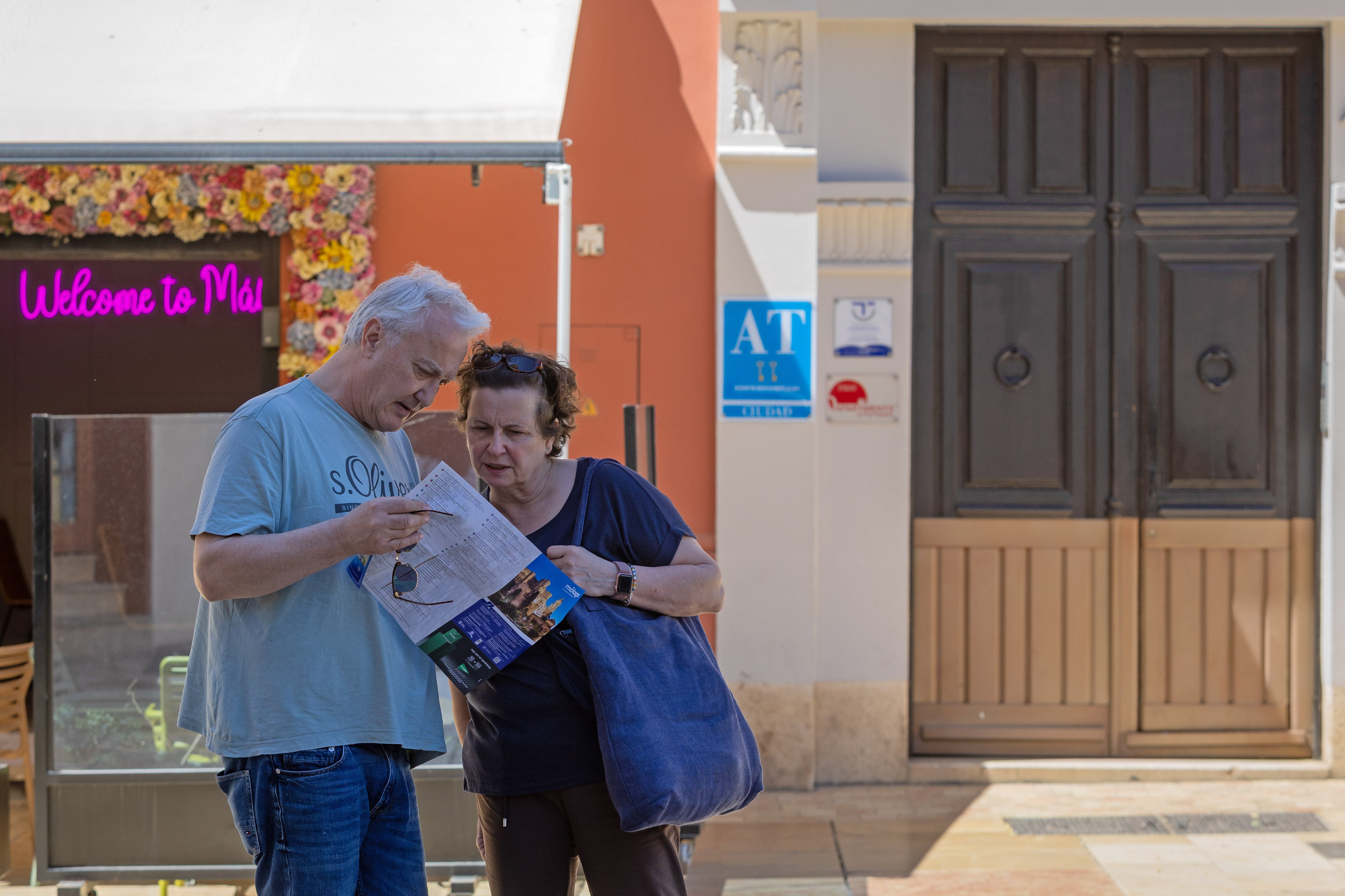 Una pareja de turistas mira un plano de la ciudad justo en la puerta de un edificio de apartamentos turísticos de calle Alcazabilla.