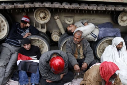 Manifestantes opositores al Gobierno egipcio descansan apoyados en un vehículo militar, ayer en la plaza de la Liberación.