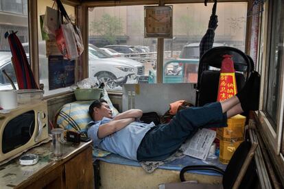 Un encargado de un parking se toma un descanso durante la hora de la comida en Pekín (China).