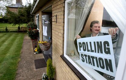 Un hombre coloca en su casa el cartel indicativo de que es un centro electoral, en Ely, donde es tradicional que las casas se conviertan en puntos de votación.