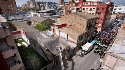 Los vecinos protestan al pie de la calle, mientras la excavadora derriba la vivienda en El Cabanyal. Al fondo, la avenida Blasco Ibañez que la alcaldesa pretende prolongar destruyendo las viviendas.