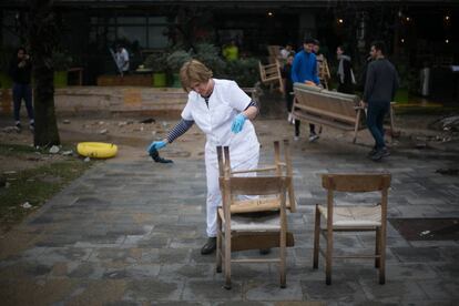 Una mujer limpia el mobiliario de un restaurante en la playa de Sant Sebastià, en Barcelona.