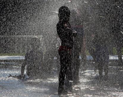 Varios niños juega con los chorros de agua para refrescarse en el parque "Madrid Río". 