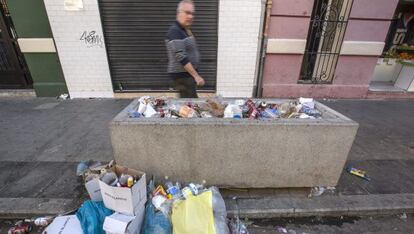 Un hombre pasa junto a un macetero lleno de basura.