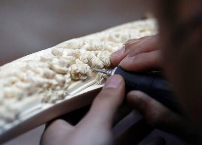 Un hombre termina los últimos detalles de una talla realizada sobre un colmillo de marfil.