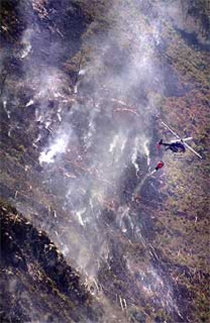 Un helicóptero lanza agua sobre el incendio de Buñol y Chiva.