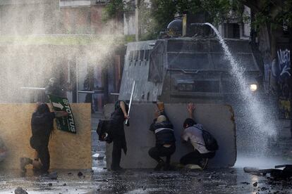 El Instituto Nacional de Derechos Humanos (INDH) ha informado de al menos 22 personas víctimas de uso abusivo de la fuerza. Los helicópteros sobrevuelan desde la noche del sábado Santiago de Chile, controlada por unos 8.000 militares. En este momento, otras cuatro regiones del país -Valparaíso, Biobío, Coquimbo y O'Higgins- se encuentran en estado de emergencia, que implica restricciones a la libertad de traslado y de reunión a los ciudadanos. En la imagen, manifestantes antigubernamentales chocan con la policía, durante las protestas contra el aumento del coste de vida, el 20 de octubre de 2019, en Santiago, Chile.