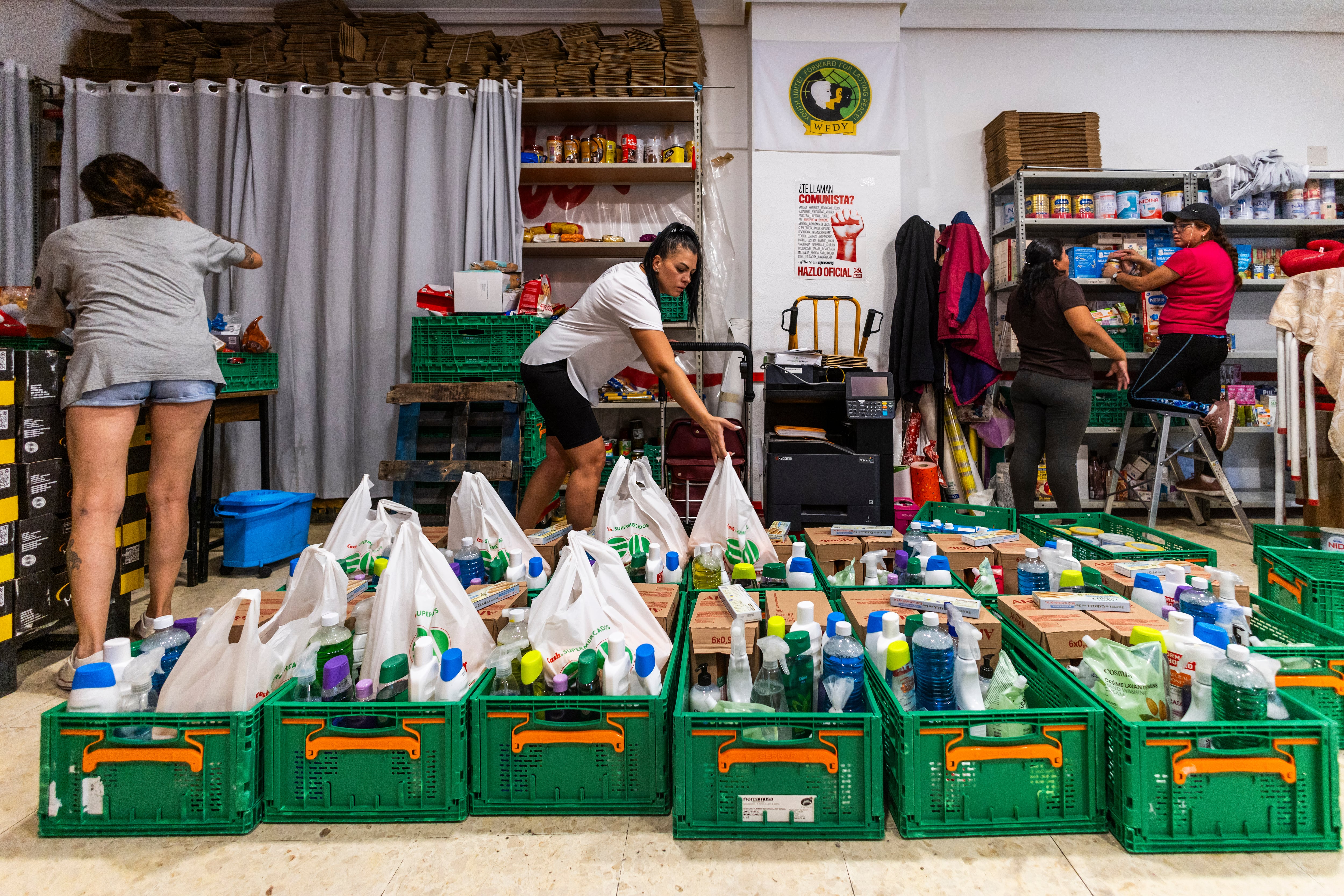 Varias mujeres organizan las cajas que repartirán a las familias con las últimas donaciones.