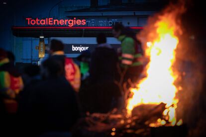 Members of the Confederation Generale du travail (CGT) labor union stand around a bonfire near a TotalEnergies gas station as they blockade a road leading to an industrial zone, in the port city of Le Havre, northwestern France, on March 21, 2023. 