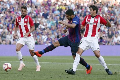 Luis Suárez (centro), del Barcelona, chuta el balón ante Mikel San José (derecha) del Athletic de Bilbao.