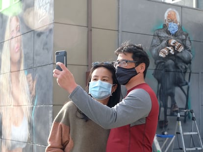 Dos personas se toman una foto junto a un mural del senador Bernie Sanders en Culver City, California.