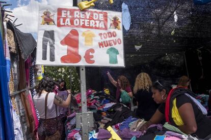 Un grupo de personas busca entre los montones de ropa en el mercadillo de Aluche.