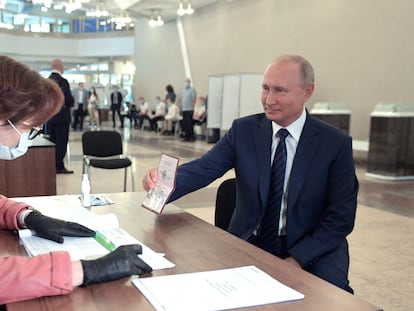 Putin enseña su pasaporte antes de votar, este miércoles en un colegio electoral de Moscú.