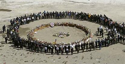 Un grupo de familiares de las víctimas del 11-S rodean una ofrenda floral en la ceremonia del aniversario de los atentados, ayer en la <i>zona cero</i> de Nueva York.