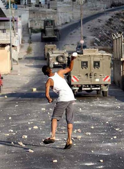 Un palestino tira piedras a vehículos israelíes en Nablus.