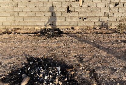 La sombra de Alí Ahmed, de 31 años y vecino de Ali Haj, señala los restos calcinados de los dos cadáveres de milicianos del ISIS que él mismo asegura quemó para “evitar que los niños amanecieran cada mañana con un panorama terrible".