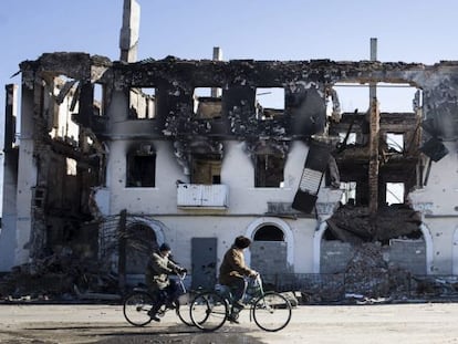 Dues persones passegen amb bicicleta davant de les restes d'un edifici de Debàltseve (Donetsk, Ucraïna), el 24 de febrer.