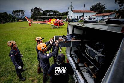 Miembros de la Policía Civil y de miembros de las fuerzas de rescate guardan cuerpos de víctimas del deslave.