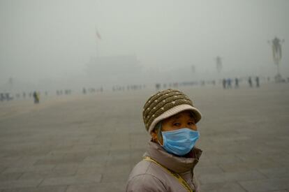 An elderly woman wearing a mask looks on as she visits Tiananmen Square during heavy pollution in Beijing on December 1, 2015. Beijing ordered hundreds of factories to shut and allowed children to skip school as choking smog reached over 25 times safe levels on December 1, casting a cloud over China's participation in Paris climate talks.          AFP PHOTO / WANG ZHAO