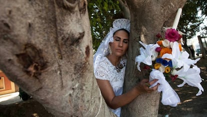 Una mujer vestida de novia abraza un árbol durante una boda entre personas y árboles.