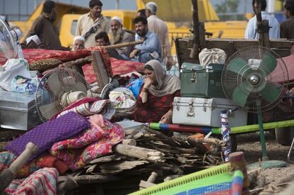 Refugiados afganos esperan con sus pertenencias en una carretera después de que el Gobierno paquistaní demoliese el asentamiento en el que vivían en Islamabad.