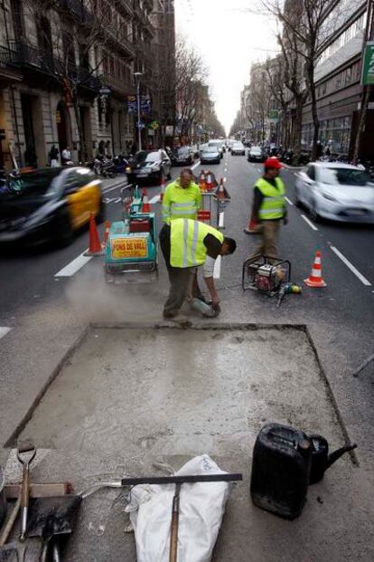 Las cuadrillas terminan de rellenar el agujero que apareció en medio de la calle Valencia, en el Eixample barcelonés.