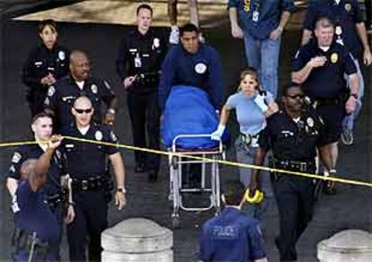 La policía saca del aeropuerto de Los Ángeles el cadáver de uno de los muertos en el tiroteo.