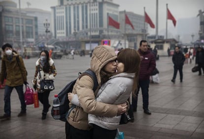 Una pareja se besa antes de entrar en la estaci&oacute;n de tren de Pek&iacute;n (China).