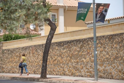 Una vecina de Dos Hermanas (Sevilla) pasea junto a un cartel electoral del PP.