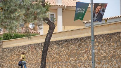 Una vecina de Dos Hermanas (Sevilla) pasea junto a un cartel electoral del PP.