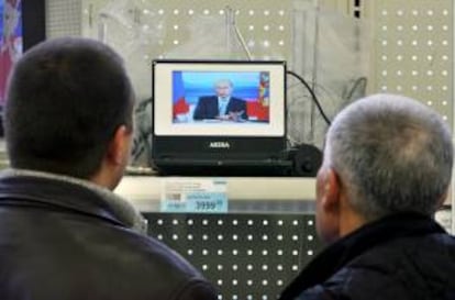 Clientes miran las pantallas durante la transmisión de un programa en director del presidente ruso, Vladimir Putin, que responde a preguntas desde el Kremlin de Moscú, en una tienda de San Petersburgo (Rusia). EFE/Archivo