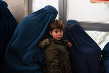 En las sillas del pasillo del Hospital Indira Gandhi, madres e hijos esperan su turno. En la imagen, dos mujeres y un niño aguardan en una sala de espera.