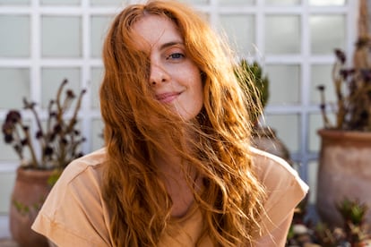 Portrait of a smiling redheaded young woman on a terrace.