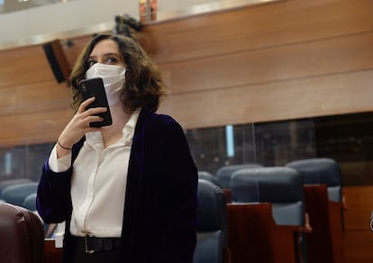 La presidenta de la Comunidad de Madrid, Isabel Díaz Ayuso (d), manda un mensaje con su teléfono a su llegada a la sesión del pleno de la Asamblea del pasado 17 de diciembre.